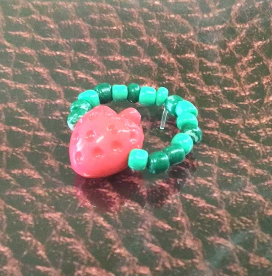 Ring with alternating green and dark green beads, with a strawberry on the center.